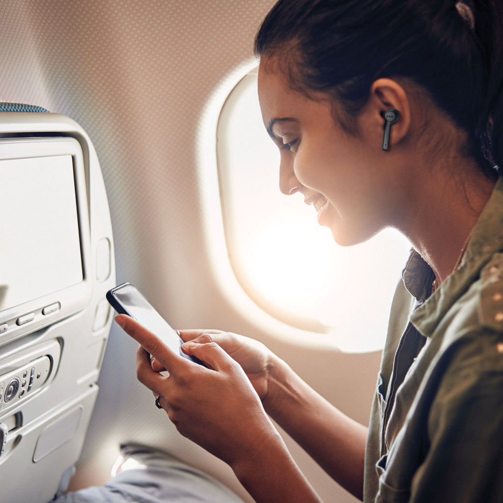 Woman using Jam Audio ANC True Wireless Earphones Black with phone on plane